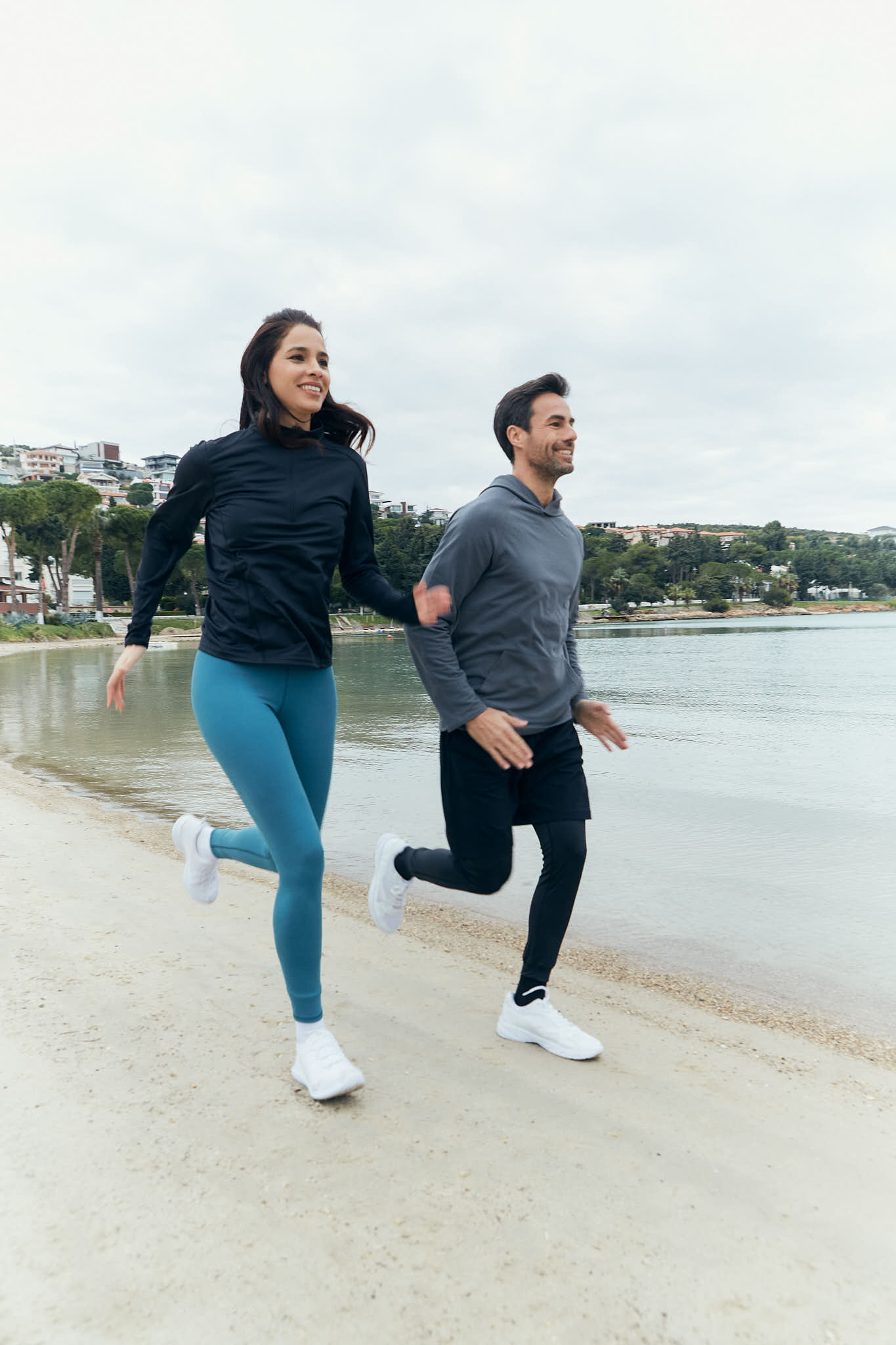 A woman and a man running in the beach.