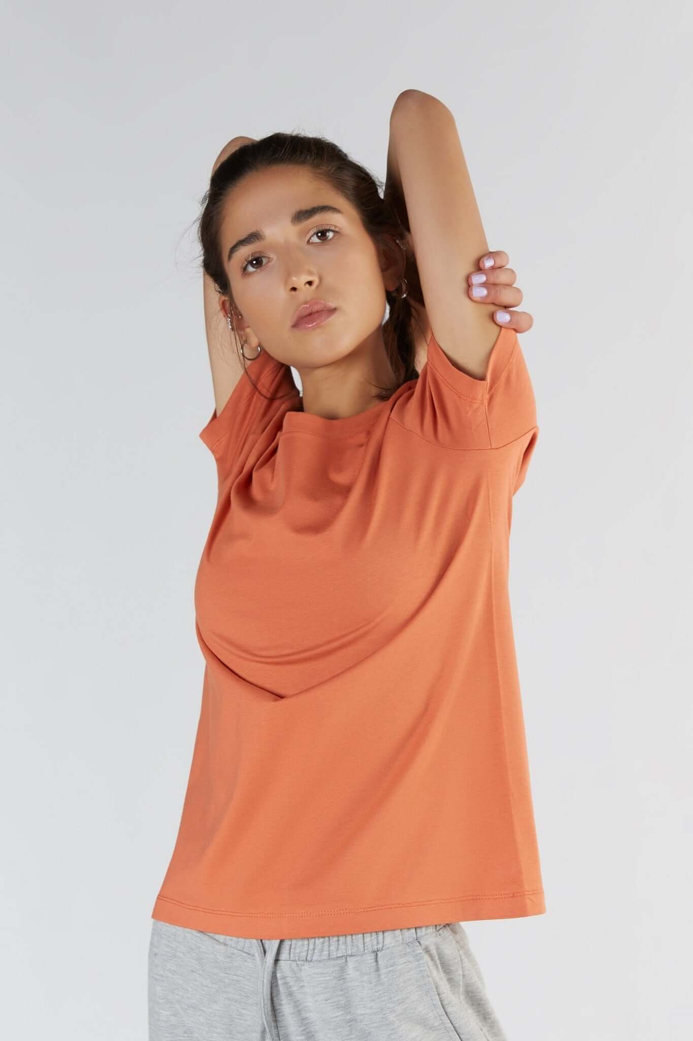 A woman posing with a Soft Orange color clothing.