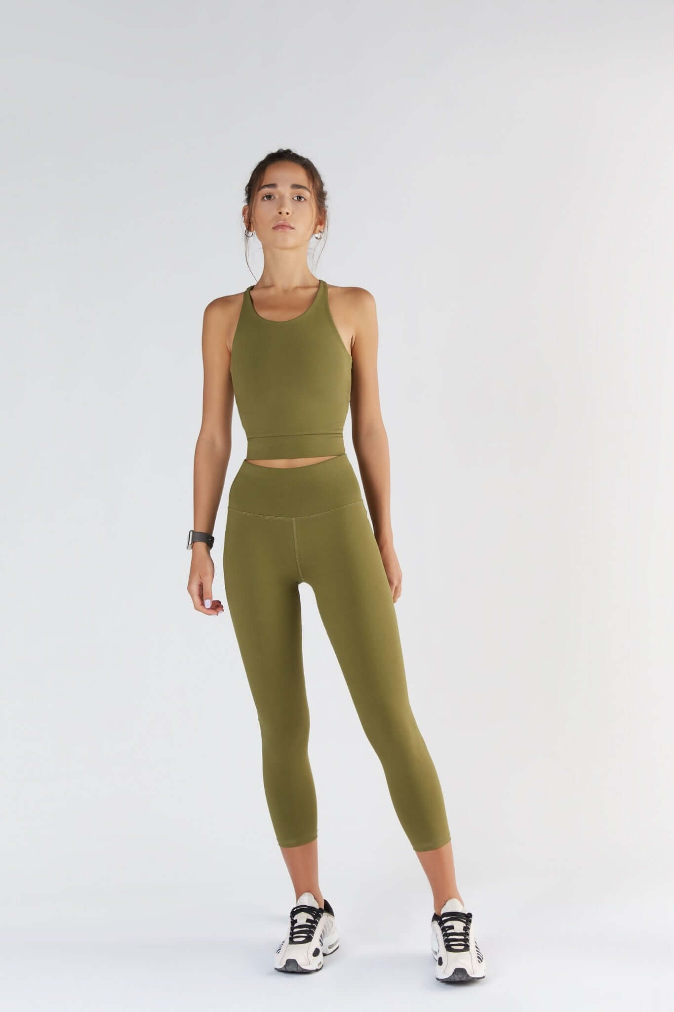 A woman posing with a Olive color clothing.