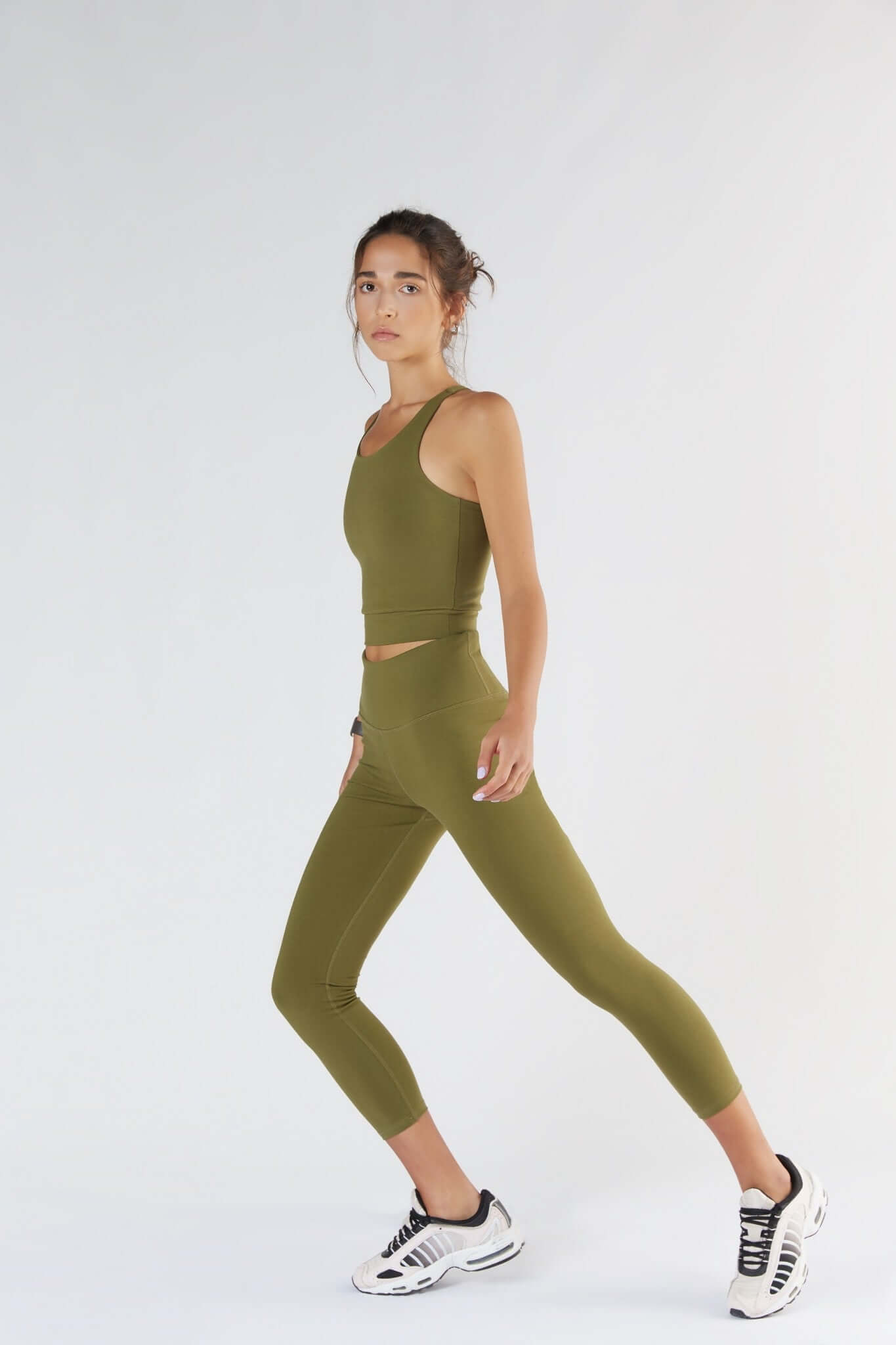 A woman posing with a Olive color clothing.