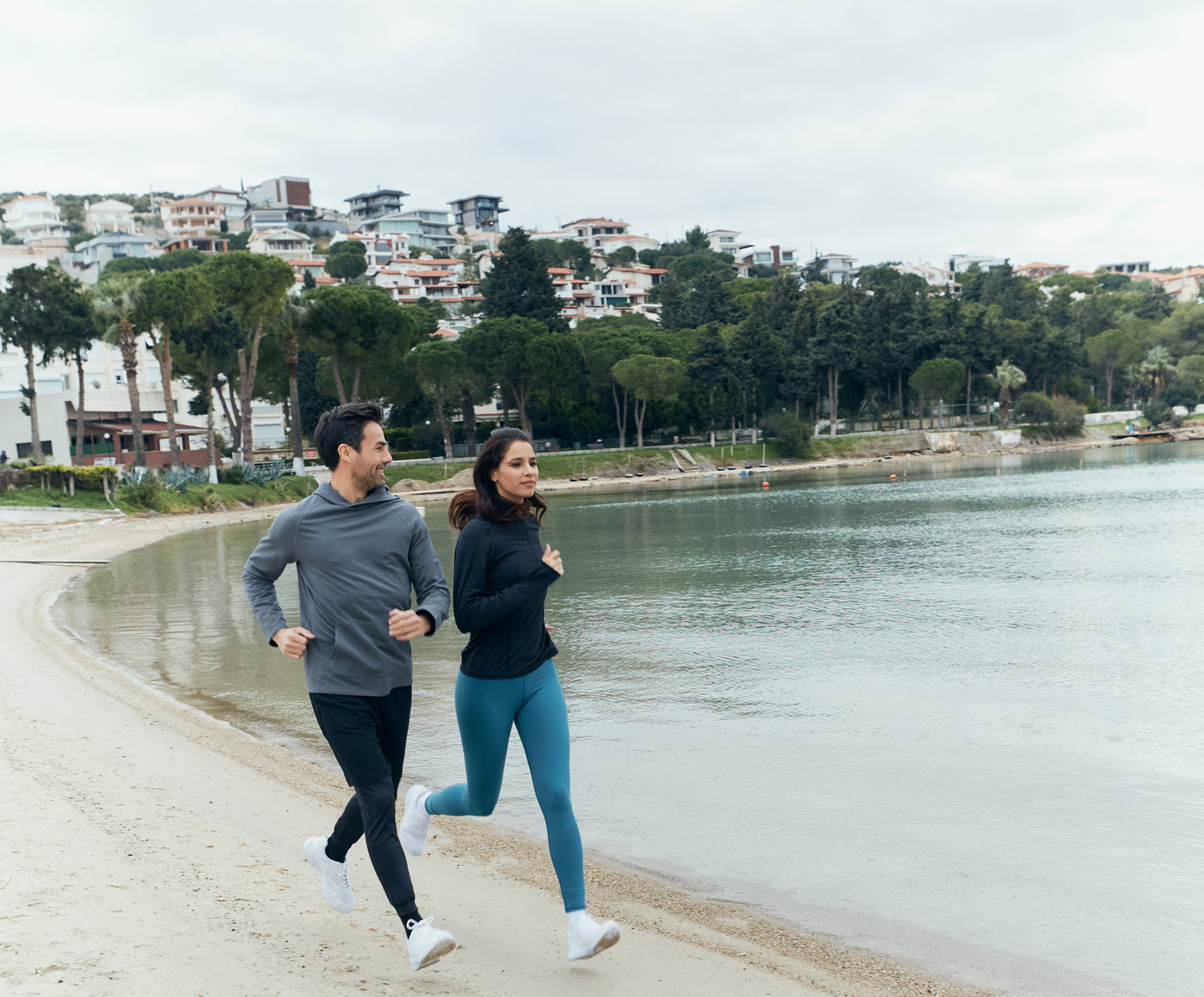 A woman and a man running in the beach.